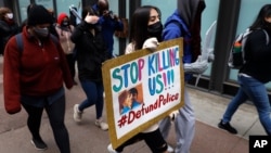 Протестующий с табличкой «Хватит нас убивать» во время мирной акции протеста в Чикаго, 14 апреля 2021 г. 