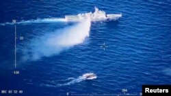 A Chinese Coast Guard ship launches what the Coast Guard says is a warning water cannon spray in the direction of a Philippine vessel at an unknown location at sea in this screen grab taken from a video released on August 8, 2023. (China Coast Guard/Handout via REUTERS) 