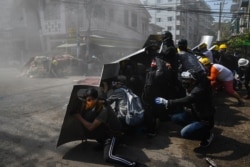 Protesters take shelter behind homemade shields after tear gas was fired during a demonstration against the military coup in Yangon on March 8, 2021.