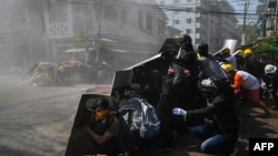 Protesters take shelter behind homemade shields after tear gas was fired during a demonstration against the military coup in Yangon on March 8, 2021.