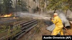 Smithville firefighter Birt Mikulec works on putting out the fire at the end of Keller Road to protect the property around the homes there near Smithville, Texas, Oct. 14, 2015. 