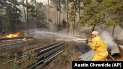 Anggota pemadam kebakaran Smithville, Birt Mikulec, berusaha untuk mematikan api di ujung Keller Road untuk melindungi harta benda dan rumah-rumah dekat Smithville, Texas, Rabu, 14 Oktober 2015 (foto: Rodolfo Gonzalez/Austin American-Statesman via AP)