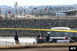 Sebuah pesawat American Airlines bersiap lepas landas sementara para penyelidik membawa potongan-potongan puing dari perairan Sungai Potomac setelah pesawat American Airlines 5342 bertabrakan dengan helikopter militer. (ANDREW CABALLERO-REYNOLDS / AFP)