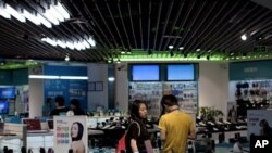 A couple browse mobile phones on display for sale at an electronic shop in Beijing, China, Wednesday, Aug. 10, 2011. China's trade growth rebounded in July despite weakening global demand and its politically sensitive trade surplus rose to its highest lev