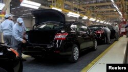 FILE - Employees work at a production line before the opening of Nissan's new plant in Aguascalientes, Mexico, Nov. 12, 2013. 