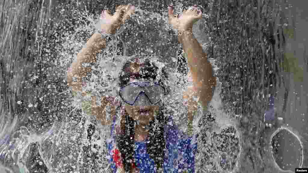 Seorang anak bermain di air mancur di Endenich, pinggiran kota Bonn, Jerman.