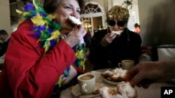 Dressed for Mardi Gras, friends enjoy beignets and coffee at the famous Cafe Du Monde in New Orleans.