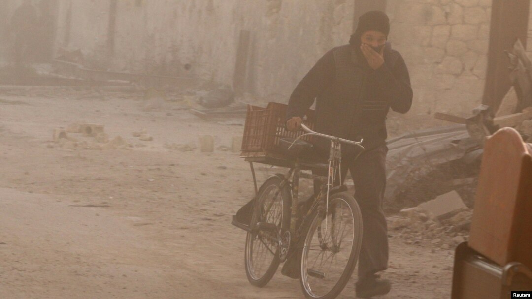 Seorang pria menutupi mukanya sambil menuntun sepedanya, saat badai debu melanda Aleppo, Suriah (foto: dok). 