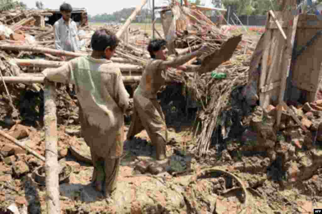 Men digging up the remains of their home in the Azakhel refugee camp, near Peshawar, following the floods that have left much of Pakistan in misery, Aug 2010