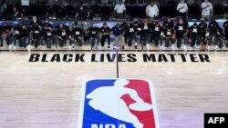 FILE - In this July 30, 2020, photo, members of the New Orleans Pelicans and Utah Jazz kneel before a Black Lives Matter logo before the start of their game at HP Field House at ESPN Wide World Of Sports Complex in Reunion, Florida. 