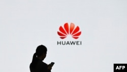 (FILES) This file photo taken on March 6, 2019 shows a staff member of Huawei using her mobile phone at the Huawei Digital Transformation Showcase in Shenzhen, China's Guangdong province. - The US administration on August 17, 2020 expanded its…