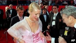 British actress Gwyneth Paltrow lifts the hem of her skirt to speak to a television reporter as she arrives for the 71st annual Academy Awards ceremony, March 21, 1999 in Los Angeles. 