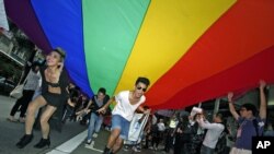 Participants hold a giant rainbow flag to symbolize lesbian, gay, bisexual, and transgender rights during a parade in Hong Kong, November 2011. (file photo)