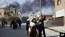 A family escapes from fierce fighting between Free Syrian Army fighters and government troops in Idlib, north Syria, March 10, 2012.