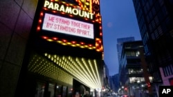 A billboard on the Paramount Theatre offers support to passers-by to observe social distancing, March 23, 2020, in Boston. 