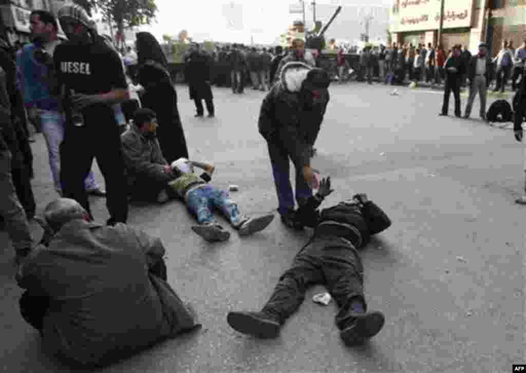 Injured anti-government protesters lie on the ground near army vehicles as they wait to be treated by medics during clashes in Tahrir, or Liberation square, in Cairo, Egypt, Wednesday, Feb. 2, 2011. Several thousand supporters of President Hosni Mubarak, 