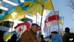 Manifestantes pro-Ucrania ondean banderas durante una protesta en las afueras de la cumbre de la UE en Bruselas.