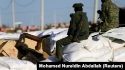 Des hommes armés gardent des sacs de nourriture livrés aux réfugiés éthiopiens au camp de Fashaga, dans l'état de Kassala, au Soudan, le 24 novembre 2020.
