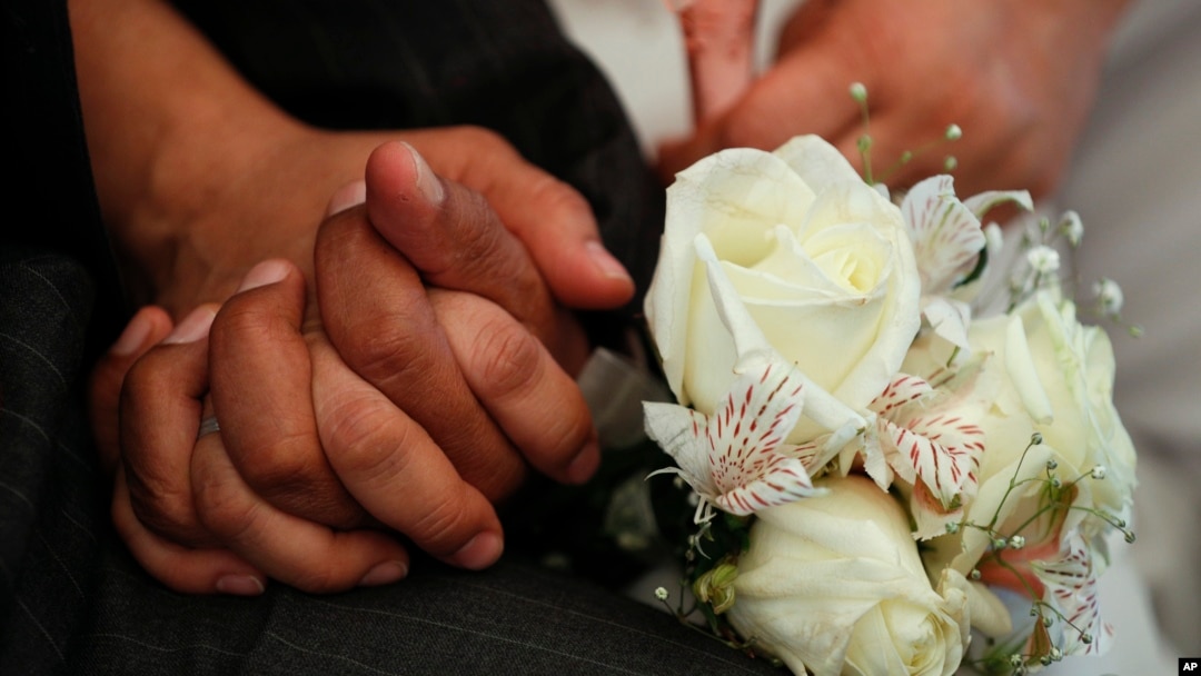 FILE - Newlyweds hold hands during a mass wedding ceremony on Valentine's Day, Thursday, Feb. 14, 2019. (AP Photo/Rebecca Blackwell)