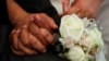 FILE - Newlyweds hold hands during a mass wedding ceremony.