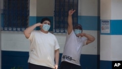 Guatemalan citizens recently deported from the United States acknowledge reporters as they stand inside a temporary shelter where the deportees are waiting for their new coronavirus test results, in Guatemala City, April 16, 2020. 