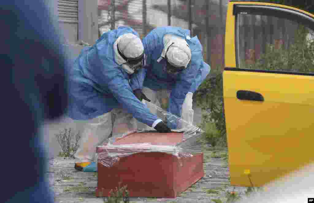 Funeral workers inside a taxi wrap a coffin with plastic containing the body of a man who died of suspected coronavirus symptoms, as he was being taken to the hospital by relatives, in Quito, Ecuador, July 15, 2020. 
