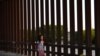 Una pequeña, que forma parte de un grupo de migrantes llegados de Centroamérica, camina junto a la valla fronteriza que separa EE. UU. y México, tras entrar al país de manera irregular, el 6 de abril de 2019.