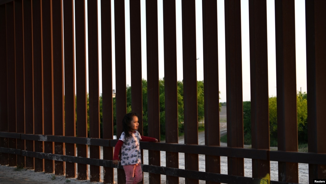 Una pequeña, que forma parte de un grupo de migrantes llegados de Centroamérica, camina junto a la valla fronteriza que separa EE. UU. y México, tras entrar al país de manera irregular, el 6 de abril de 2019.