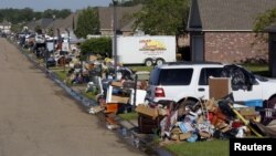 Debris is piled up along the street as victims of flood damage work to dig out in St. Amant, Louisiana, Aug. 21, 2016.