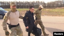 Mantan anggota Angkatan Laut AS, Trevor Reed, dibawa menuju sebuah pesawat oleh pasukan Rusia di Moskow dalam aksi pertukaran tahanan antara AS dan Rusia pada 27 April 2022. (Foto: RU24/Handout via Reuters)