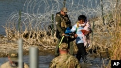 ARCHIVO - Agentes detienen a migrantes en la frontera entre Texas y México, en Eagle Pass, Texas, el 3 de enero de 2024