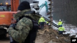 FILE - Workers build the first part of a wall intended to block migrants pushed by Belarus, in what the European Union calls a "hybrid attack," from crossing illegally into EU territory, in Tolcze, near Kuznica, Poland, on the border with Belarus Jan. 27, 2022.