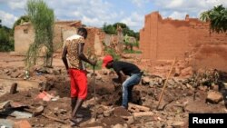 Two men dig up bricks to re-use from a destroyed church in Kapende, a Congolese neighbourhood in Lucapa, Angola, Oct. 19, 2018. 