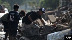 Personas rescatan pertenencias en las calles de Planeta, municipio de La Lima, departamento hondureño de Cortés, el 9 de noviembre de 2020, luego del paso del huracán Eta, ahora degradado a Tormenta Tropical.