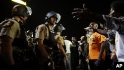 FILE - Officers and protesters face off along West Florissant Avenue in Ferguson, Missouri, Aug. 10, 2015.