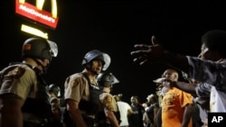 FILE - Officers and protesters face off along West Florissant Avenue in Ferguson, Mo., Aug. 10, 2015. 