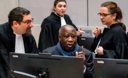 FILE - Former Ivory Coast president Laurent Gbagbo talks to his members of his legal team at the International Criminal Court in The Hague, Netherlands, Feb. 6, 2020.