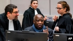 FILE - Former Ivory Coast President Laurent Gbagbo talks to his attorneys at the International Criminal Court in The Hague, Netherlands, Feb. 6, 2020.