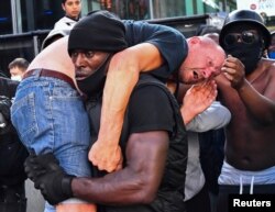 A protester carries an injured counterprotester to safety, near the Waterloo station during a Black Lives Matter protest following the death of George Floyd in Minneapolis police custody, in London, June 13, 2020.
