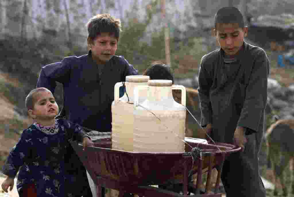 Niños paquistaníes transportan contenedores de agua en una carretilla después de haberla recolectado en una bomba de agua en las afueras de Islamabad.