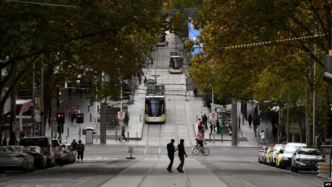 FILE - Pedestrians cross a deserted street in Melbourne's central business district on May 11, 2020, as Australia starts to ease its COVID-19 restrictions. 