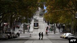 FILE - Pedestrians cross a deserted street in Melbourne's central business district on May 11, 2020, as Australia starts to ease its COVID-19 restrictions. 