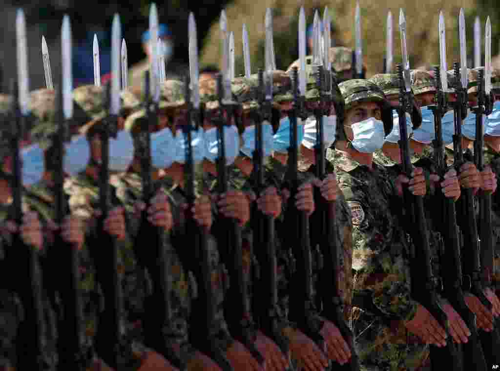 نمایی از سربازان صربستان در یک مراسم رسمی که همه آنها ماسک به صورت زده‌اند. 