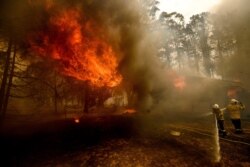 Firefighters battle the Morton Fire as it consumes a home near Bundanoon, New South Wales, Australia, Jan. 23, 2020.