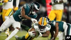 El corredor de los Packers de Green Back Josh Jacobs salta para anotar antes de que lo detenga el cornerback de los Eagles de Filadelfia Quinyon Mitchell en el encuentro de comodín del domingo 12 de enero del 2025. (AP Foto/Derik Hamilton)