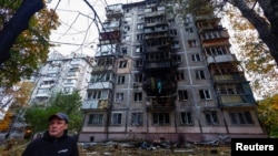 A resident stands in front of an apartment building damaged by a Russian drone strike, amid Russia's attack on Ukraine, in Kyiv, Ukraine October 30, 2024. 