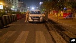 An Indian police, left, and a paramilitary personnel stop a vehicle during a complete lockdown amid growing concerns of coronavirus in Gauhati, India, March 24, 2020.