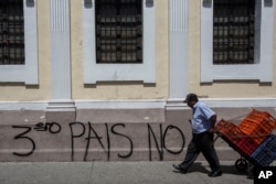 A man carries boxes past the Spanish message: "No third country" near Congress in Guatemala City, July 30, 2019.