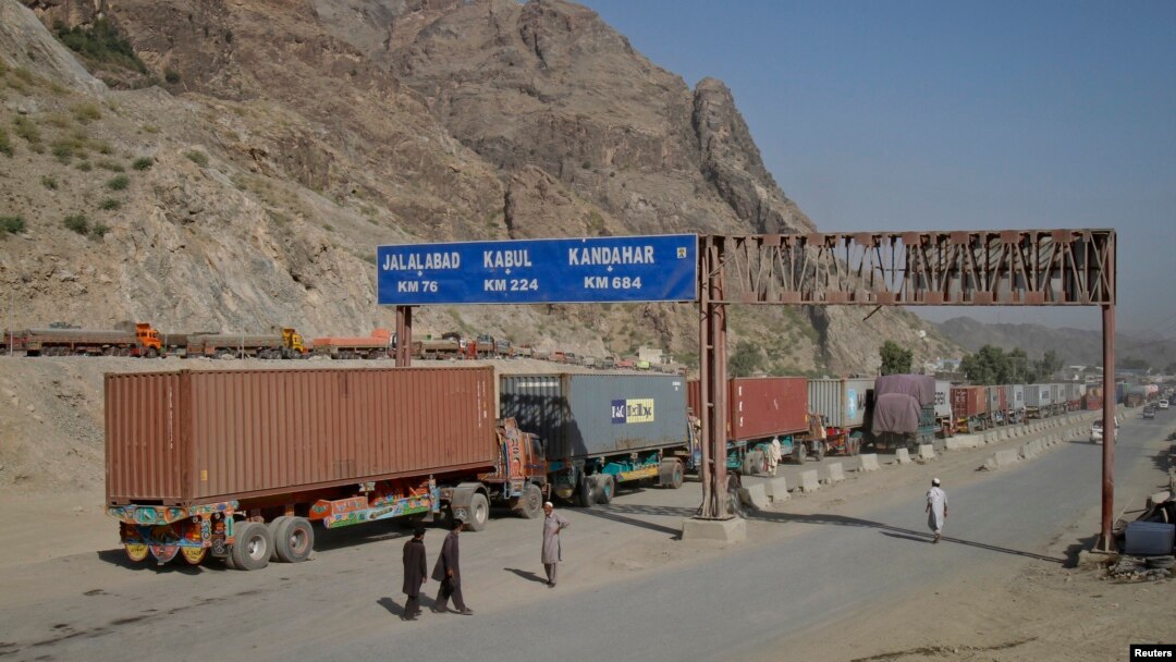 Beberapa orang pria berjalan di dekat papan penunjuk jalan yang menunjukkan jarak menuju beberapa kota di Afghanistan, saat sebuah truk melintasi perbatasan kota Torkham, perlintasan perbatasan Afghanistan-Pakistan (foto: dok). 