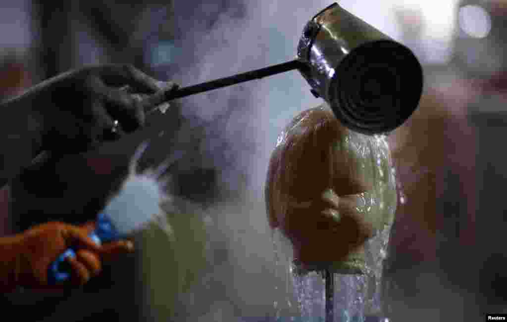 An employee pours water over a doll&#39;s head before brushing its hair inside the toy factory owned by Norberto Garcia in Buenos Aires, Argentina, July 28, 2014.
